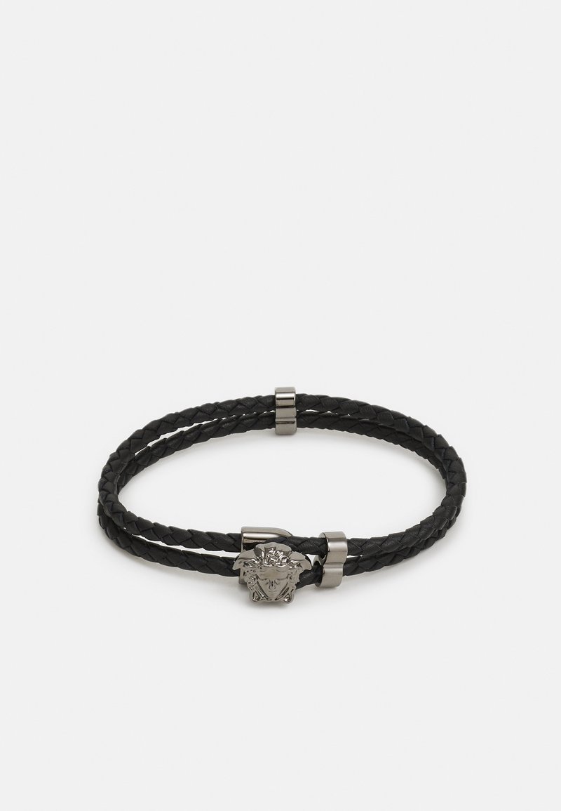 Musta sõlmitud nahkbracelet, millel on hõbedase tooni lõvi pea embleem ja metallic aktsentdetailid. Topeltülekande disain turvaliseks istuvuseks.