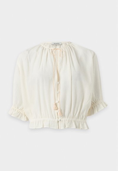 Blouse blanche texturée avec manches trois-quarts, encolure ronde avec cordon, boutons sur le devant et taille et poignets élastiqués froncés.