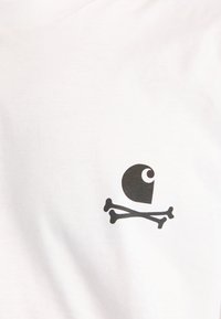 Símbolo de ojo abstracto negro sobre dos huesos cruzados en un fondo de tejido blanco liso.