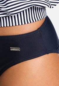 Navyblauwe bikinionderkant van glad materiaal met een zilveren merketiket. Heeft een aansluitend ontwerp en platte naden, in combinatie met een gestreepte top.