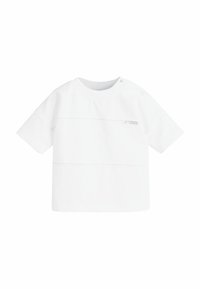 Chemise blanche à manches courtes en coton avec un col rond, présentant des détails de coutures horizontales et une petite étiquette sur le devant.