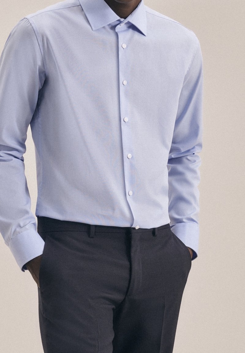 Lichtblauw overhemd met lange mouwen en een button-down kraag, met een gladde textuur en subtiele glans, gedragen met donkere broek.