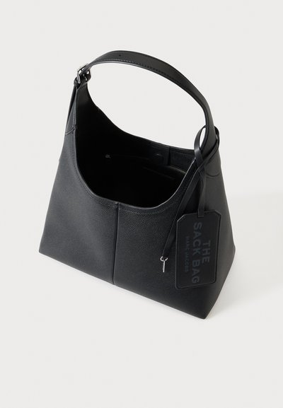 Sac à bandoulière en cuir noir texturé avec une large poignée et une étiquette indiquant "THE SACK BAG MARC JACOBS" attachée.