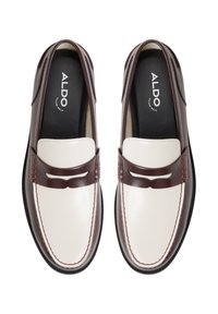 Braune und weiße Lederloafer mit einem gestickten Design, ausgestattet mit einem dekorativen Riemen über der Vorderseite und strukturierten Akzenten an den Seiten.