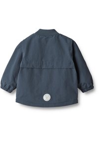 Marineblauwe jas met een geribbelde kraag, elastische manchetten en een ronde logo patch op de achterkant. Glad weefsel met een ontspannen pasvorm.