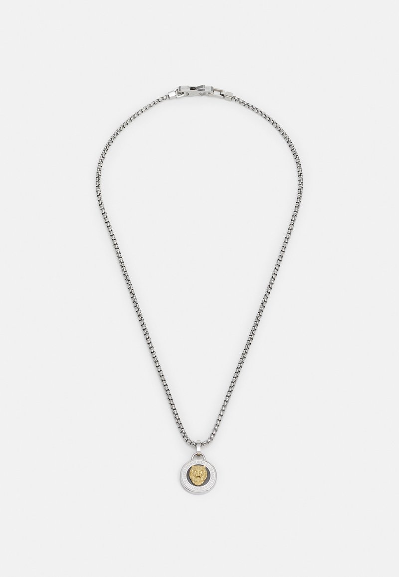 Collier en chaîne argentée mettant en avant un pendentif rond avec un emblème de lion doré, une bordure détaillée et une fermeture à clapet.