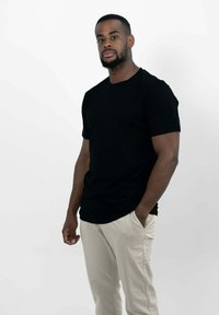 Zwarte t-shirt met korte mouwen en een ronde hals, gedragen met lichtbeige broeken. Eenvoudig ontwerp, gladde textuur, met een comfortabele pasvorm.