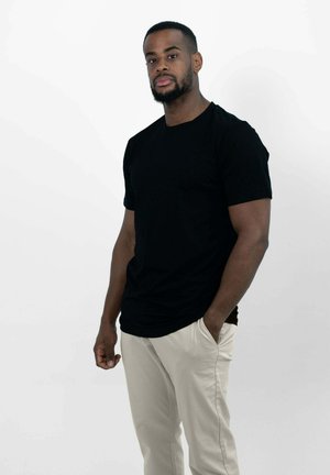 Zwarte t-shirt met korte mouwen en een ronde hals, gedragen met lichtbeige broeken. Eenvoudig ontwerp, gladde textuur, met een comfortabele pasvorm.