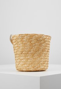 Cesto portaoggetti intrecciato realizzato in paglia naturale, forma rotonda, colore beige chiaro, con due manici superiori per un facile trasporto.