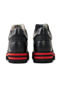 Czarne skórzane buty z teksturowanym wykończeniem, czerwono-czarnymi paskami na podeszwie oraz oznakowanym tyłem pięty.