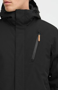 Juodas vandeniui atsparus džemperis su aukšta kaklu, reguliuojama kapucha ir užtrauktuku uždaroma krūtinės kišenė su odiniais akcentais. Lygus paviršius, modernus dizainas.