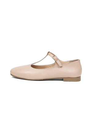 Beige platte leren schoen met T-bandje, kleine hak en gespsluiting, vanuit de zijkant getoond tegen een witte achtergrond.