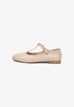 Beige platte leren schoen met T-bandje, kleine hak en gespsluiting, vanuit de zijkant getoond tegen een witte achtergrond.