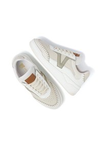White and light beige sneakers with a stitched design, mesh accents, a textured tongue, and a tan logo patch on the side.