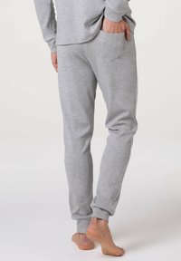 Pantaloni del sudore in cotone grigi con vestibilità affusolata, polsini elasticizzati e tasca posteriore. Texture liscia, design semplice e stile casual.