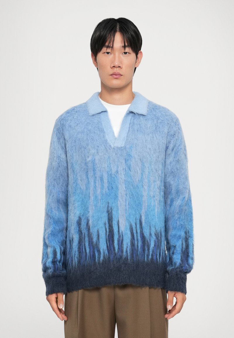 Maglione blu sfocato a gradiente con colletto, caratterizzato da un blu chiaro nella parte superiore e un blu scuro all'orlo. Vestibilità morbida e aspetto testurizzato.