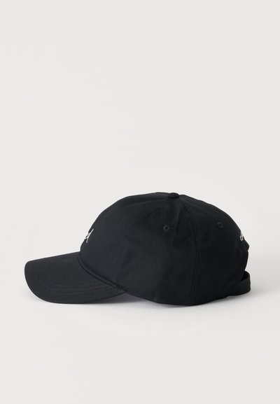 Casquette de baseball noire vue de profil sur un fond clair uni, avec des coutures visibles et une visière incurvée.