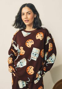 Brown ribbed sweatshirt with orange cookie and blue milk carton patterns. Relaxed fit with long sleeves and round neckline.