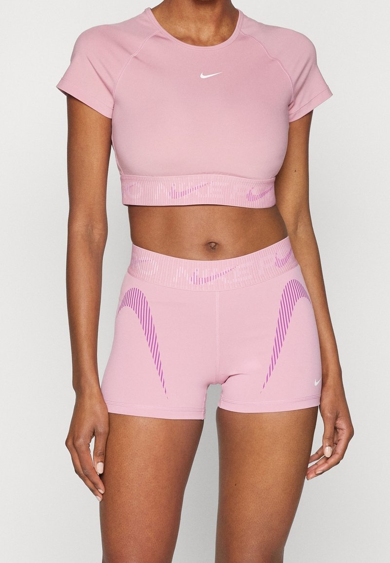 Rosa träningscropp och shorts-set i stretchigt material, med ribbad midja och subtila lila ränder, samt en vit logotyp.