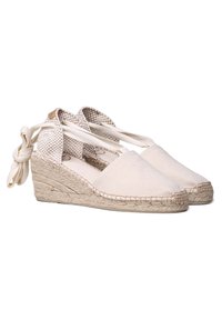 Espadrillas con zeppa realizzate in tela beige con suola in juta intrecciata. Presentano lacci in cotone alla caviglia e una fodera in cotone testurizzato.