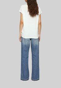Helles blauer und weißer gestreifter Kurzarm-Top kombiniert mit locker sitzenden, ausgewaschenen blauen Jeans mit fransigem Saum.