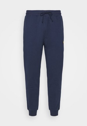 Pantalones jogger azul marino con cintura de cordón, piernas entalladas, puños acanalados y un pequeño logo amarillo en la parte superior lateral.