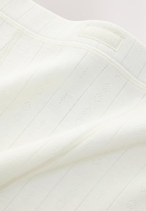 Tela blanca de punto con textura acanalada, que presenta pequeños patrones de diamante y una etiqueta con "NEXT" cerca del borde superior.