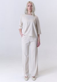 Beige zijde top met 3/4 mouwen, gecombineerd met op maat gemaakte beige broek. Zachte textuur, ontspannen pasvorm en minimalistisch ontwerp. Eenvoudige instapschoenen.