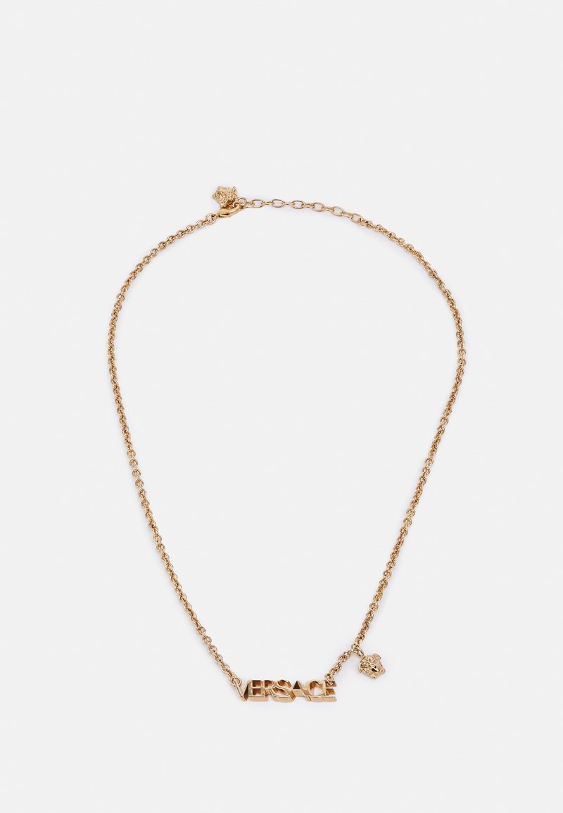 Collier chaîne en or avec le logo "VERSACE" et un petit pendentif tête de Méduse sur fond blanc.