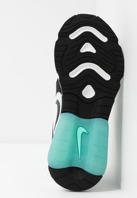 Svart och vit sneakersula med akvamarinfärgade detaljer; har texturerad gummi, upphöjda mönster och en framträdande Nike-logotyp i mitten.