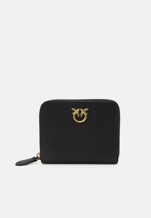 Zwarte leren portefeuille met een gouden logo-accent, ritsluiting en getextureerd oppervlak. Compact rechthoekig model met een kleine leren ritskuip.