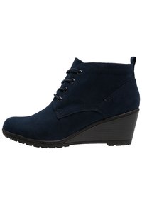 Bottes cheville en daim bleu marine avec talon compensé, dotées de six œillets pour les lacets et d'une texture lisse. Détail de couture latérale présent.