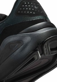 Musta urheilukenkä, jossa on teksturoitu verkkopäällisosa, kumipohja ja tunnistettava uritettu muotoilu. Kenkässä on logoyksityiskohdat ja pehmustettu kantapääalue.