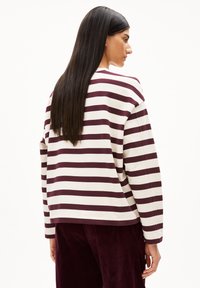 Gestreepte longsleeve top in crème en bordeaux, met brede horizontale strepen, een losse pasvorm en een ronde halslijn. Corduroy broek zichtbaar.