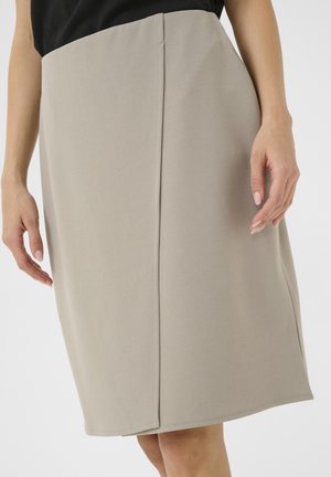 Knee-pikkusega beež pliiatsiseelik, millel on sile tekstuur, puhtad jooned ja peened õmblused. Nähtavat riistvara ega mustreid pole.