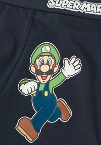 Tmavě modré šortky s velkým potiskem karikatury postavy v zelené čepici a montérkách, s bílými rukavicemi a hnědými botami.