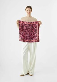 Seidenschal mit einem auffälligen Leopardenmuster in Pink und Schwarz, umrahmt von einem kontrastierenden roten Rand, vor einem schlichten Hintergrund gehalten.