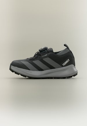 Juodi ir pilki Adidas Terrex bėgimo takais batai su Climaproof tinkleliu, su sukamu užsegimu ir tvirtu padu lauko naudojimui.