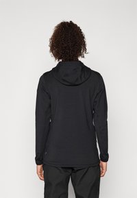 Felpa nera a maniche lunghe con un design aderente, dotata di cappuccio con cordini, spalle senza cuciture e una finitura in tessuto testurizzato.
