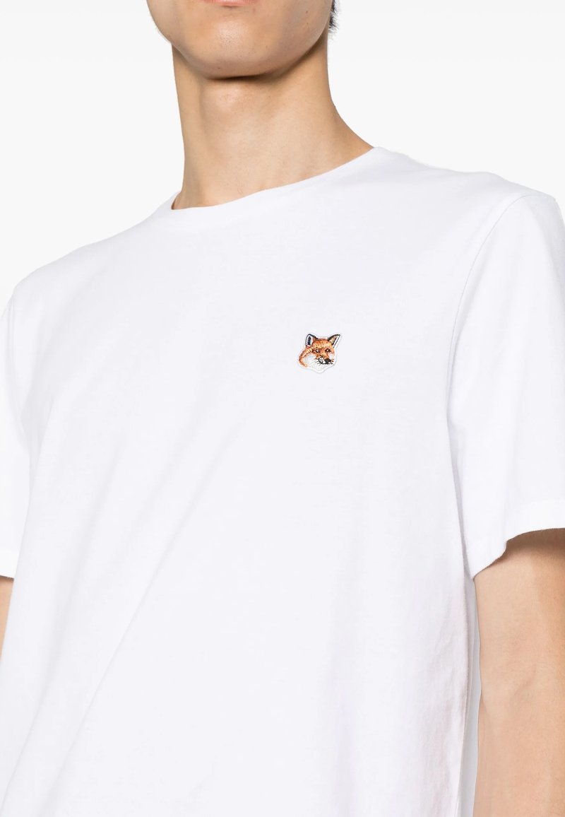T-shirt bianco in cotone con scollo rotondo e maniche corte, caratterizzato da un design di testa di volpe ricamato sul lato sinistro del petto.
