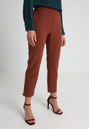 Bruine, op maat gemaakte broeken met een rechte pijpdesign, gemaakt van een gladde stof. Dragen met een donkergroene top en bordeauxrode hoge hakken.