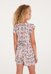Robe courte colorée à motifs avec des manches courtes volantées, en tissu léger, une taille cintrée et une combinaison de motifs en losanges rouges, bleus et blancs.