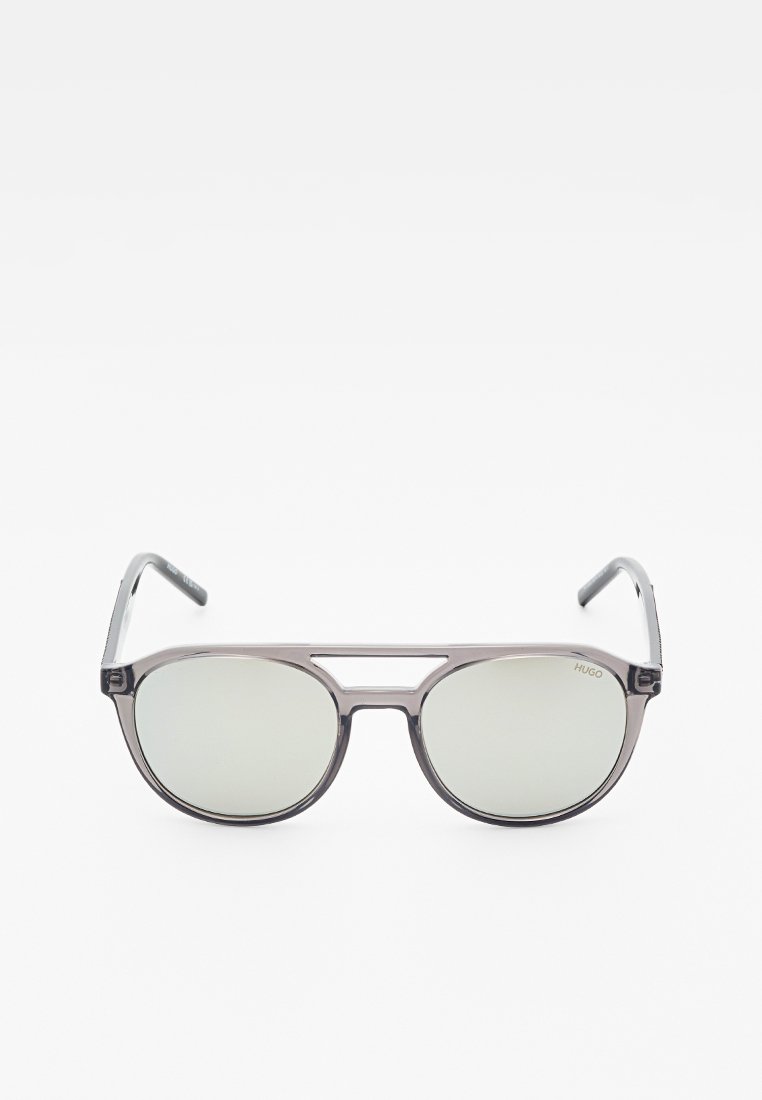 Occhiali da sole trasparenti grigi in stile aviator con lenti grigie riflettenti e design a doppio ponte, con il marchio "HUGO" sulla lente.