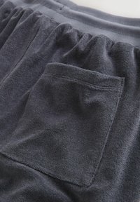 Pantalones cortos de algodón gris oscuro con cintura elástica y tejido texturizado. Presenta un único bolsillo trasero con detalle de costura.