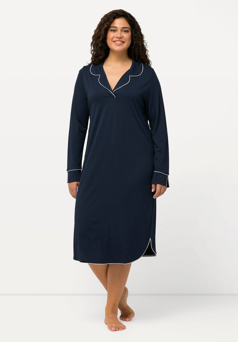 Camicia da notte navy in morbido tessuto, con maniche lunghe, colletto a patta e piping bianco lungo il colletto e i polsini; lunghezza al ginocchio con spacchi laterali.