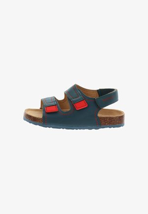 Sandalo aperto per bambini con cinturini in pelle blu scuro, dettagli in velcro rosso, suola in sughero imbottita e cinturino regolabile alla caviglia.