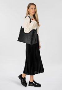 Borsa a tracolla nera in pelle con forma rettangolare. Presenta due manici corti, una texture liscia e cuciture sottili. Design semplice senza hardware visibile.