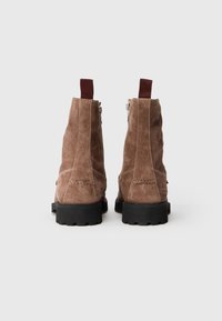 Rudos suede auliniai batai su tekstūriniu paviršiumi, su elastingais traukikliais ir šoninėmis užtrauktukais, ir tvirtu juodu guminiu padu.