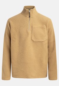 Beige fleece genser med høy krage, halv glidelås foran og brystlomme. Strukturert stoff med et mykt og koselig utseende.
