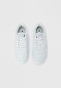 Άσπρα δερμάτινα αθλητικά παπούτσια με ομαλή υφή, στρογγυλή μύτη, διακοσμητικές τρύπες και κορδόνια· λογότυπο στο πλάι.
